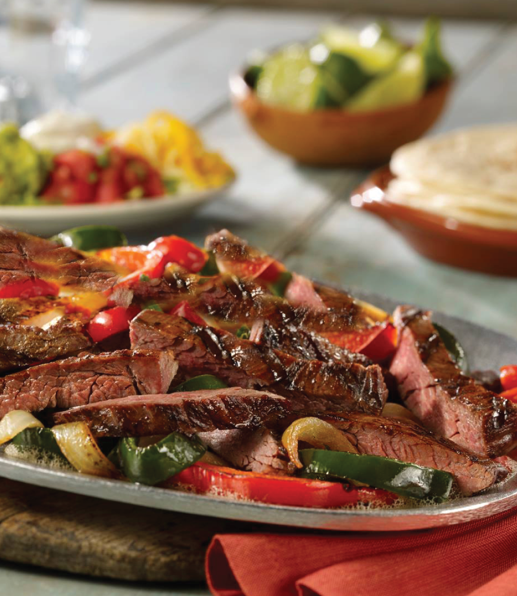 Steak fajitas with sides, limes and tortillas on the table