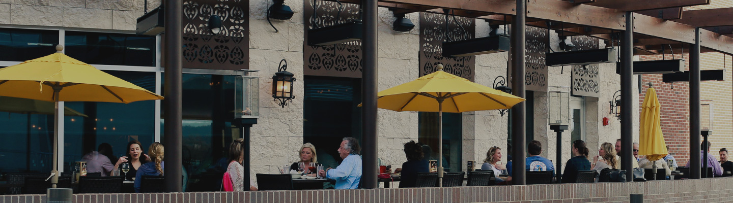 Guests dining outside on outdoor patio under yellow umbrellas