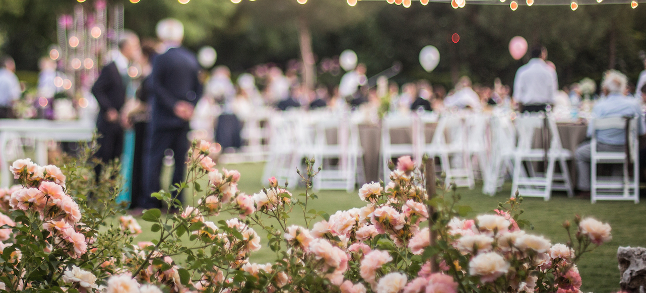 Image of a gathering of people at a wedding with flowers in the foreground