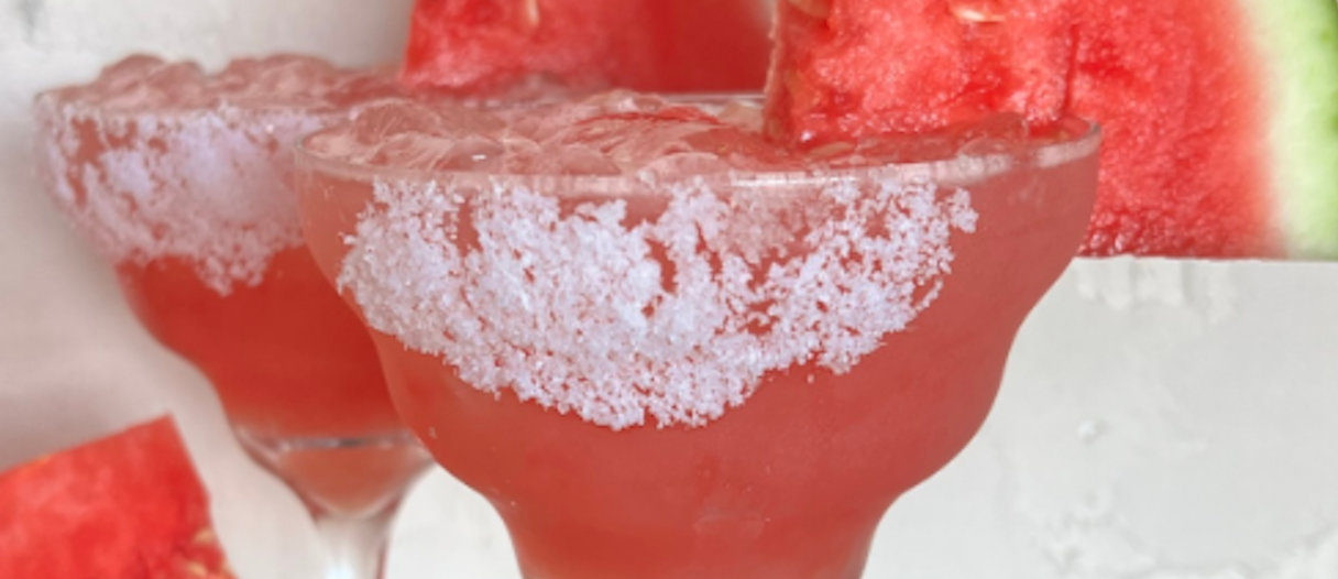 Uncle Julio's Watermelon Margarita of the Month in glass cups with sugar and a slice of watermelon on the rim of the glass.
