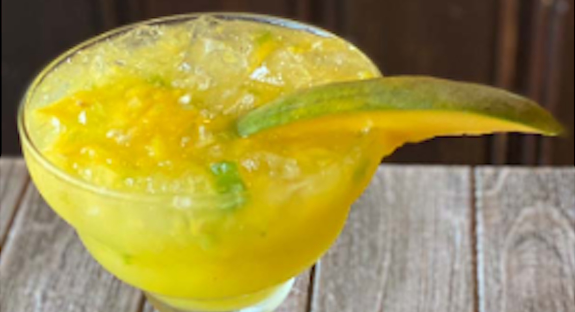 Uncle Julio's September Margarita of the Month, Mango Jalapeno, in a margarita glass with a mango slice on the rim.