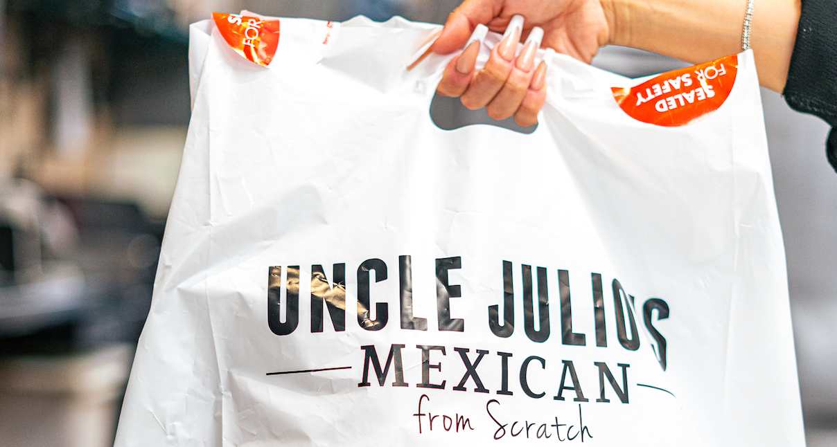 Uncle Julio's worker holding an Uncle Julio's To-Go order in her hands.