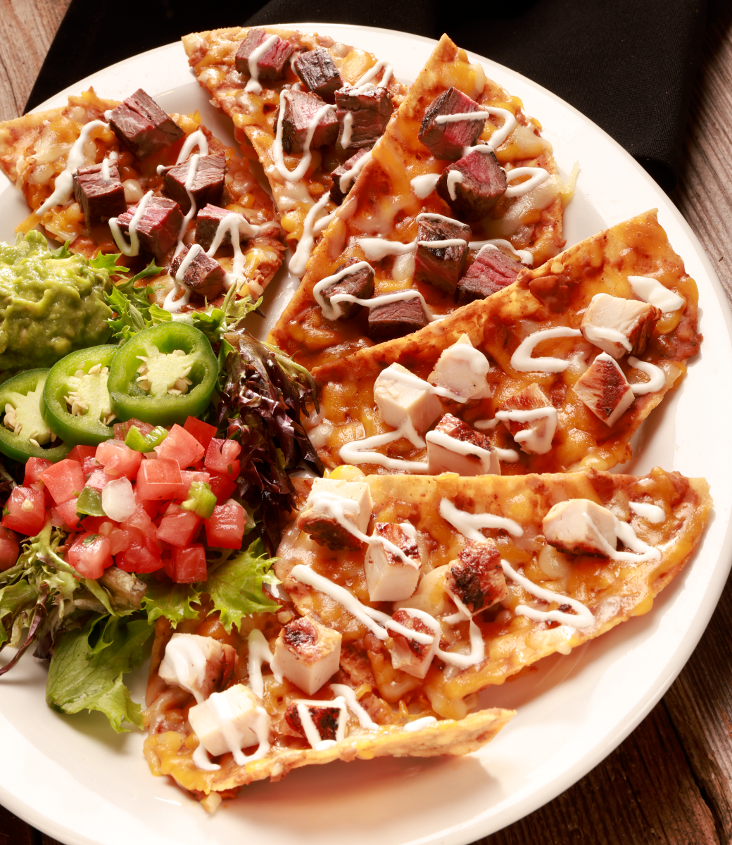 Combination fajita nachos served on plate with pico de gallo
