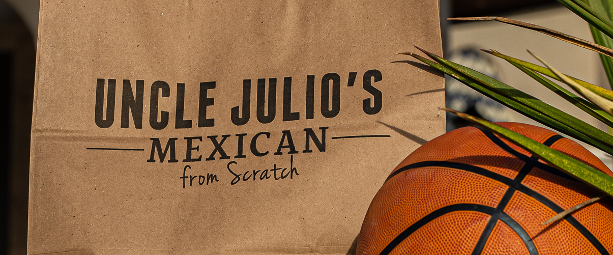 Uncle Julio's to go bag next to a basketball